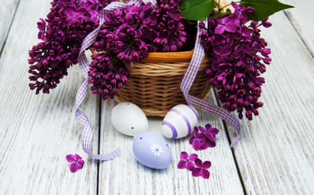 easter eggs and fresh lilac flowers on a old wooden backgroundの写真素材