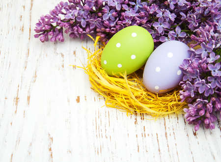 easter eggs and fresh lilac flowers on a old wooden backgroundの写真素材