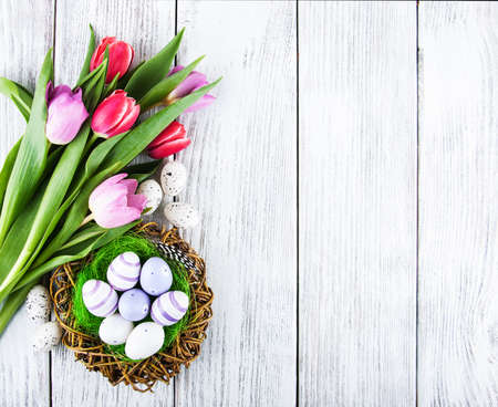easter background with eggs in nest and pink tulipsの写真素材