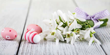 snowdrops and easter eggs on a old wooden tableの写真素材