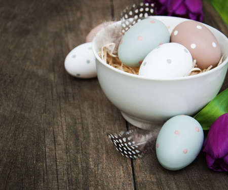 Bowl with easter eggs on a old wooden tableの写真素材