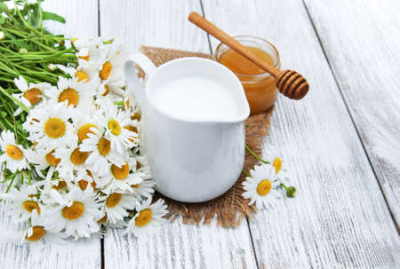 jug with milk  and chamomile flower on a wooden tableの写真素材