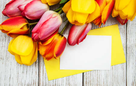 Spring tulips flowers with greeteing card on a old wooden  backgroundの写真素材