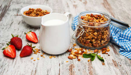 Homemade baked granola in a glass jar, milk and strawberriesの写真素材