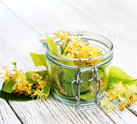 linden flowers in a jar on a old wooden tableの写真素材