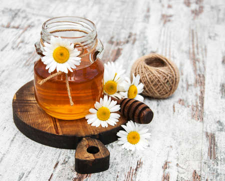 Honey  and chamomile on a old wooden tableの写真素材