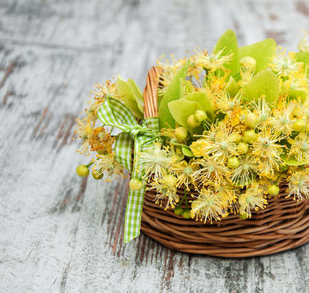 Basket  with linden flowers on a old wooden tableの写真素材