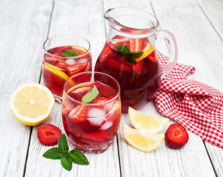 Glasses of lemonade with strawberries, lemon and mint on a old wooden tableの写真素材