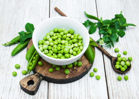 green peas  on rustic white wooden background