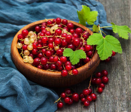Bowl with red currant on a old wooden table