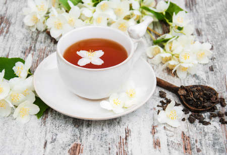Cup of tea with jasmine flowers on a wooden backgroundの写真素材