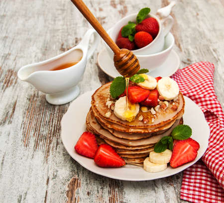 Pancakes with  fresh strawberries and bananas on a wood backgroundの写真素材