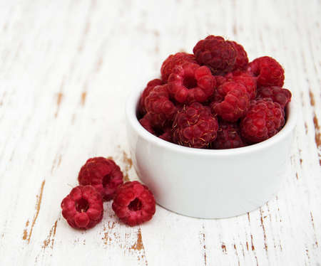 Bowl with raspberries on a old wooden background