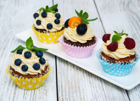 Cupcakes with fresh berries on a old wooden tableの写真素材