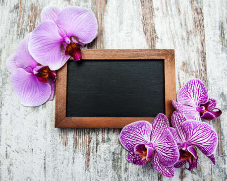 Blackboard and pink  orchids on a old wooden tableの写真素材