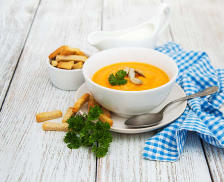 Pumpkin soup with fresh pumpkins on a old wooden tableの写真素材