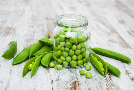 Jar with green peas on a wooden tableの写真素材