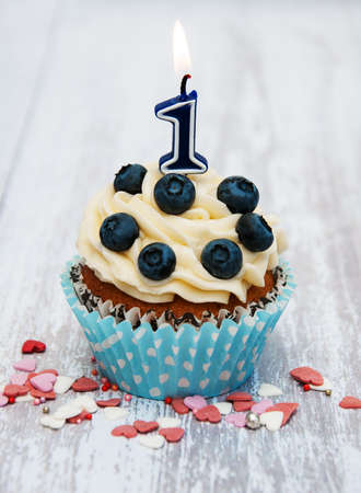 Cupcake with a numeral one candle on a tableの写真素材