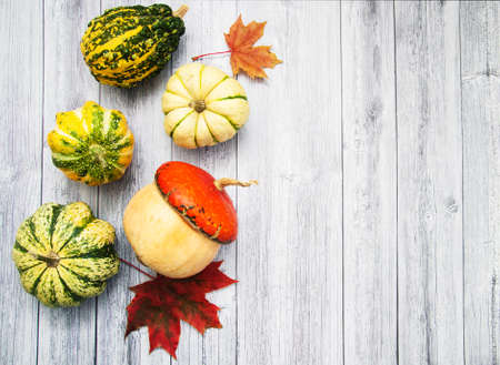 Pumpkins with autumn leaves on a old wooden tableの写真素材