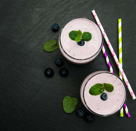Glasses with blueberry yogurt and fresh berries on a black stone backgroundの写真素材