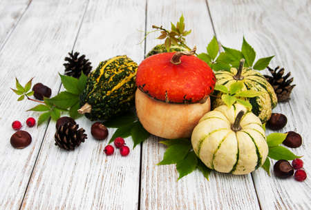 Pumpkins with autumn leaves on a old wooden tableの写真素材