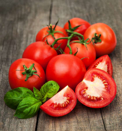 Fresh tomatoes with green basil on a old tableの写真素材