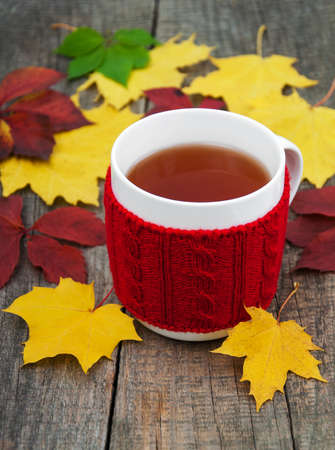 Cup of tea and autumn leaves on a old wooden tableの写真素材
