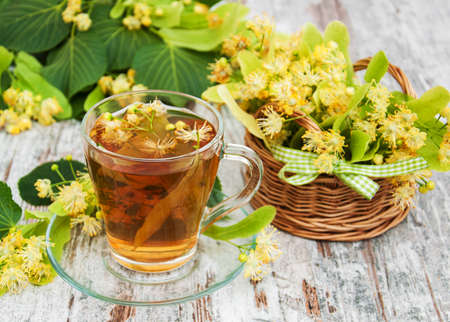 cup of herbal tea with linden flowers on a old wooden backgroundの写真素材