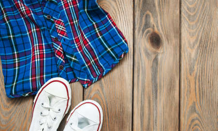 Checkered shirt with white sneakers on a wooden tableの写真素材