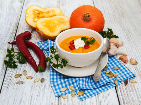 Pumpkin soup with fresh pumpkins on a old wooden tableの写真素材