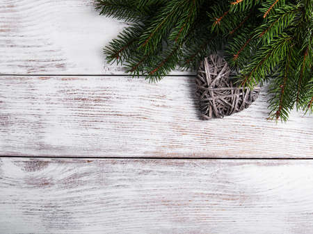 Christmas tree branches with heart decoration on a wooden backgroundの写真素材