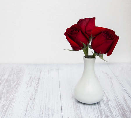 Vase with red roses on a old wooden background