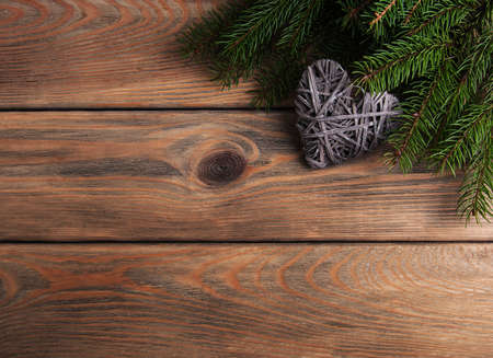 Christmas tree branches with heart decoration on a wooden backgroundの写真素材