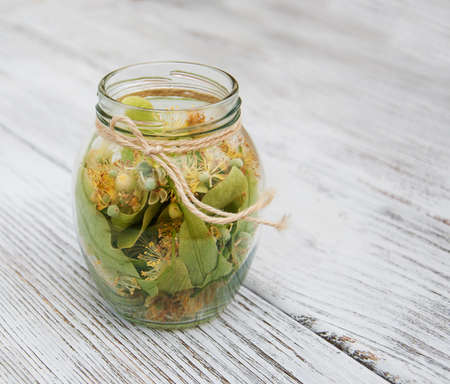 linden flowers in a jar on a old wooden tableの写真素材