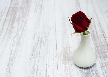 Vase with red rose on a old wooden backgroundの写真素材