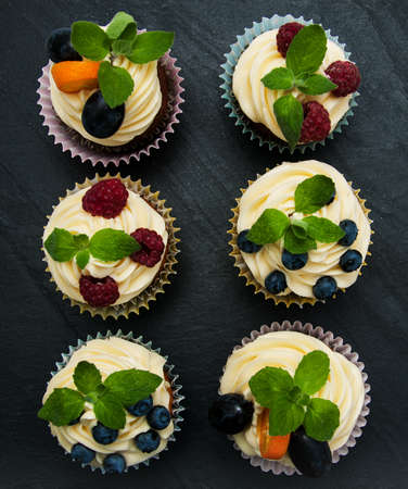 Cupcakes with fresh berries on a black stone backgroundの写真素材