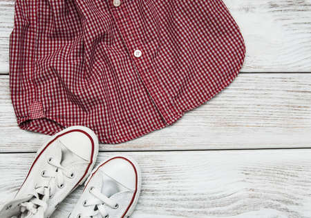 Checkered shirt with white sneakers on a wooden tableの写真素材
