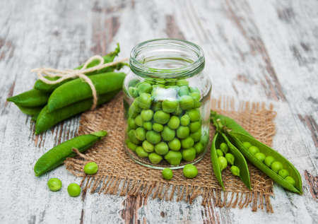 Jar with green peas on a wooden table