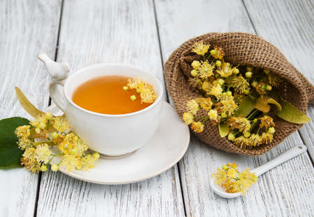 cup of herbal tea with linden flowers on a old wooden backgroundの写真素材