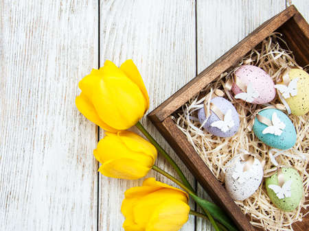 Easter eggs and tulips on a wooden tableの写真素材