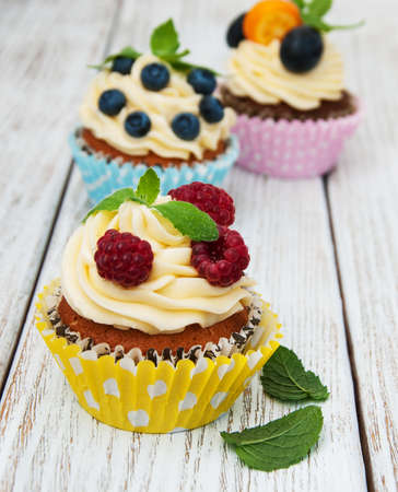 Cupcakes with fresh berries on a old wooden tableの写真素材