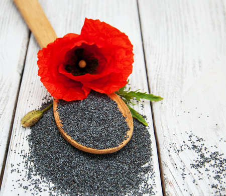 Poppy seeds and poppy flowers on a wooden backgroundの写真素材