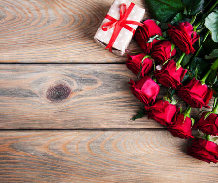 Red roses and gift box on a wooden backgroundの写真素材