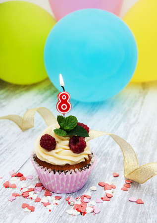 Cupcake with a numeral eight candle on a table