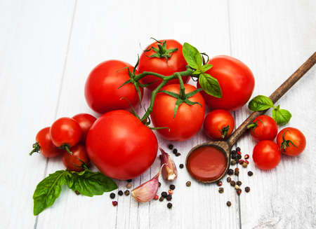 Spoon with tomato sauce and fresh tomatoes on a tableの写真素材