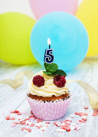 Cupcake with a numeral five candle on a tableの写真素材