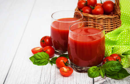 Glasses with tomato juice and fresh tomatoes on a tableの写真素材