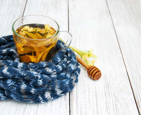 Scarf and Linden tea with honey on a wooden tableの写真素材