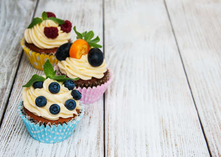 Cupcakes with fresh berries on a old wooden tableの写真素材