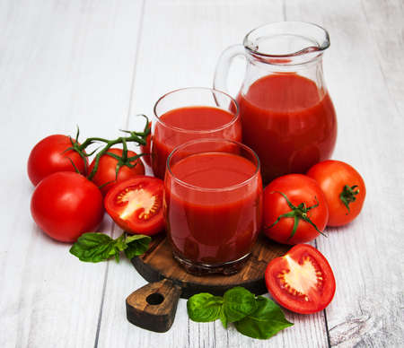 Glasses with tomato juice and fresh tomatoes on a tableの写真素材